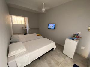 a bedroom with a bed and a tv on the wall at POUSADA AMARELA in Itanhaém