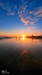 two people standing on the beach at sunset at POUSADA AMARELA in Itanhaém