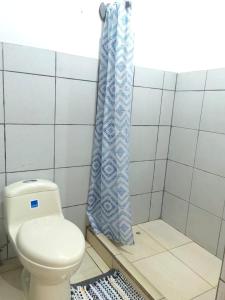 a bathroom with a toilet and a shower curtain at Casa Mariana in Alajuela City