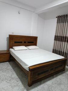 een slaapkamer met een groot bed met witte lakens bij Sara Appartments in Colombo