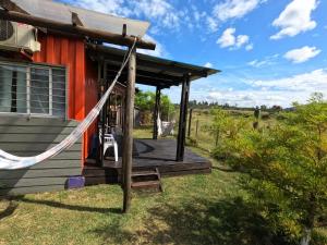 a porch of a red house with a hammock at La pausa in Piriápolis