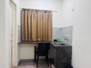 a kitchen with a sink and a desk with a chair at Hotel Madiwala Grand in Bangalore