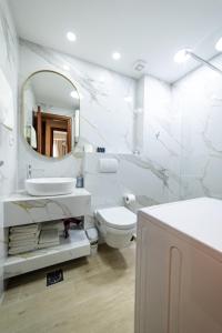 een badkamer met een wastafel, een toilet en een spiegel bij Apartments 28 in Podgorica