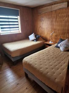 two beds in a small room with a window at Ruta Austral - Coyhaique in Coihaique