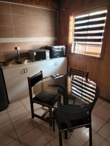 a kitchen with a table and two chairs and a microwave at Ruta Austral - Coyhaique in Coihaique