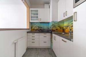 a kitchen with white cabinets and a colorful wall at Apartament Gąsiorowskich 4 Friendly in Poznań