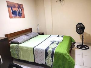 una camera con un letto con una coperta verde e un ventilatore di Estudio Céntrico Express a Santa Cruz de la Sierra