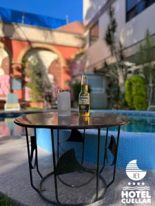 a bottle of beer sitting on a table next to a pool at Hotel Cuellar in Tula de Allende