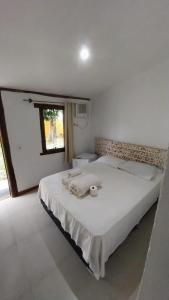 a white bedroom with a bed with a candle on it at Geribali Suítes in Búzios