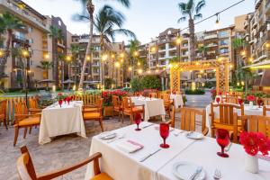 a restaurant with white tables and chairs and palm trees at Villa del Arco Beach Resort & Spa in Cabo San Lucas