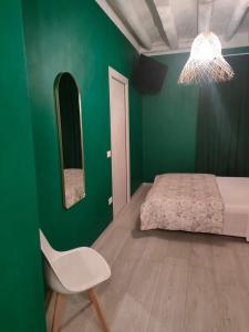 a green bedroom with a bed and a white chair at Residenza Sant'Andrea Smeraldo in Chioggia