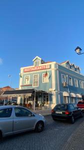 due auto parcheggiate di fronte a un edificio di Apartamentos Turisticos Queluz a Queluz