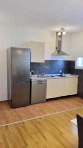 una cucina con frigorifero in acciaio inossidabile e pavimenti in legno di Villa Neptune Apartments a Vrboska (Verbosca)