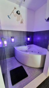 ヴルボスカにあるVilla Neptune Apartmentsの紫色の照明付きのバスルーム(白い大型バスタブ付)