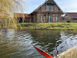 un kayak rojo en el agua frente a una casa en Fachwerkhaus am See mit privat Strand, en Warendorf