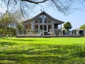 una casa con giardino d'inverno con prato verde di Ty Canol a Newborough