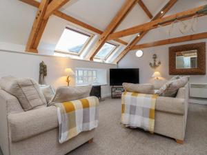 a living room with two chairs and a flat screen tv at The Boathouse Seahouses in Seahouses