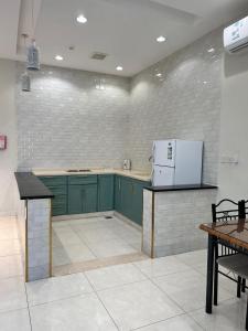 a kitchen with green cabinets and a white refrigerator at سرايا ان شاليهات وغرف فندقية in Jazan