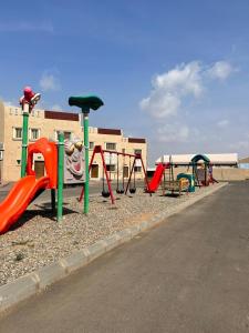 una fila di attrezzature per il parco giochi di fronte a un edificio di سرايا ان شاليهات وغرف فندقية a Jazan