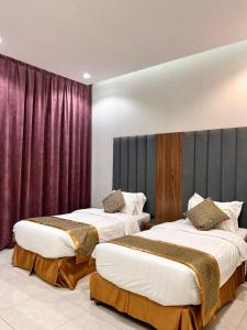 twee bedden in een kamer met paarse gordijnen bij سرايا ان شاليهات وغرف فندقية in Jazan