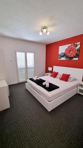 a bedroom with a large white bed with red walls at Villa Neptune Apartments in Vrboska