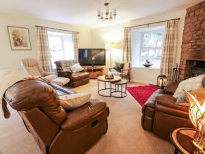 a living room with leather furniture and a fireplace at Oakbank in Dumfries