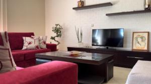 a living room with red furniture and a flat screen tv at Kylian Apartments in Sarandë
