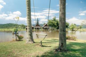 a swing hanging from two palm trees in front of a lake at Celeiro da Lagoa - Chalé confortável em meia à Natureza A apenas 8 km de distância da praia central de Balneário Picarras e a 15 Parque Beto Carrero World in Piçarras