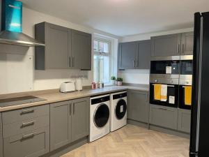 a kitchen with gray cabinets and a washer and dryer at Modern 6bedroomall ensuite in Birkenhead Free Parking and Wifi in Wallasey