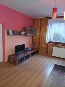 ein Wohnzimmer mit einem Flachbild-TV auf einem Holzboden in der Unterkunft Chalupa u Jánošíka in Terchová