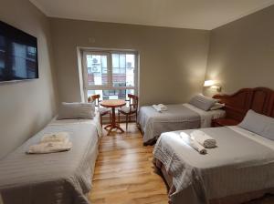 um quarto com duas camas e uma mesa e uma janela em Hotel Goya BA em Buenos Aires