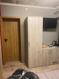 a room with a wooden cabinet and a tv on a wall at 4 PORY ROKU POKOJE GOŚCINNE in Kamesznica