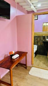 a room with a wooden table and a pink wall at Balcones del Paraíso in Baños