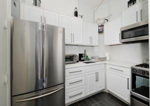 een keuken met witte kasten en een roestvrijstalen koelkast bij Magnificent 2 BD 1 BR At Mid West in New York