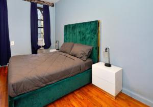 een slaapkamer met een groot bed met een groen hoofdeinde bij Magnificent 2 BD 1 BR At Mid West in New York