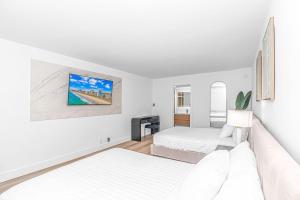 a white bedroom with two beds and a tv at Fifth and Ocean in Myrtle Beach