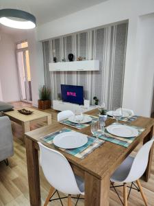 ein Esszimmer mit einem Holztisch und weißen Stühlen in der Unterkunft 2E Apartment Myslym Shyri in Tirana