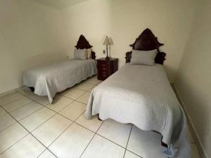 een slaapkamer met 2 bedden en een tegelvloer bij Casa los Mariachis centro in San Juan de los Lagos