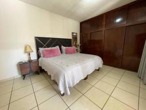 um quarto com uma cama grande e almofadas cor-de-rosa em Casa los Mariachis centro em San Juan de los Lagos