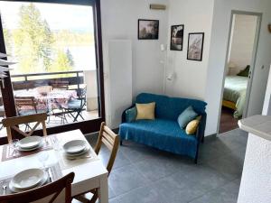 un soggiorno con un divano blu e un tavolo di Beau Duplex, au bord du lac Saint-Point a Malbuisson Altre 16 foto