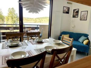 a dining room with a table with chairs and a couch at Beau Duplex, au bord du lac Saint-Point in Malbuisson