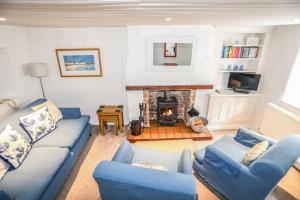 a living room with blue couches and a fireplace at Blue Cottage in Beaumaris