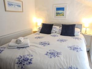 a bed with blue and white sheets and pillows at Blue Cottage in Beaumaris