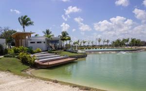 a house on the shore of a river with palm trees at Dream villa with pool & garden view in Vista Cana in Punta Cana