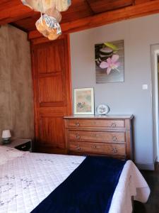 - une chambre avec un lit et une commode en bois dans l'établissement Les orchidées, à Mouillac