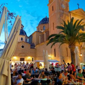 een groep mensen die aan tafels voor een gebouw zitten bij Casa Francesca Altea piscina y aparcamiento privado in Altea