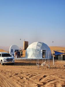 a car parked in front of a tent in the desert at Bubbles Domes Private Cmp in Al Wāşil