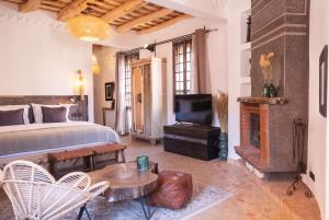 a bedroom with a bed and a tv and a fireplace at Eden Boutique Hotel in Tamellalt