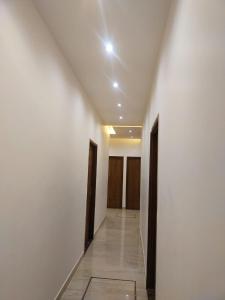 un pasillo con paredes blancas y un pasillo con puertas marrones en HOTEL HIVIN AND PEANCE - TOP RATED AND SERCH PROPERTY AMRITSAR en Amritsar