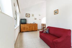 een woonkamer met een rode bank en een tv bij Villetta con giardino a 5 minuti dal mare in Flumini di Quartu